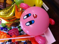 balloons with faces on them sitting on a table in a room filled with balloons and streamers