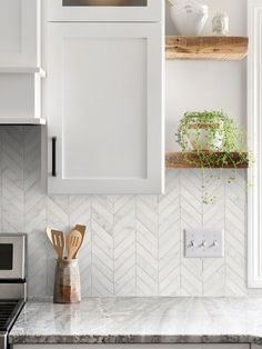 a kitchen with white cabinets and wooden utensils on the counter top next to an oven