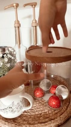 two hands are reaching for some chocolates on a tray in front of soap dispensers