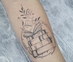 a tattoo on the arm of a person with books and leaves coming out of it