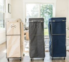 three different colored storage bags sitting on top of a hard wood floor next to a window