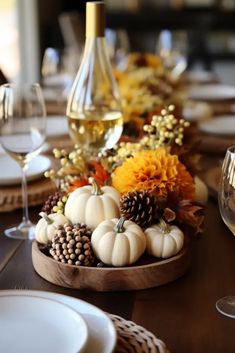 the table is set with white pumpkins, pine cones and other autumn decorations on it