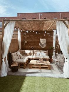 an outdoor living area with white curtains and furniture