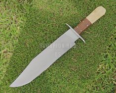 a knife that is laying in the grass with a wooden handle on top of it