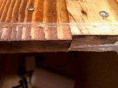 a close up of a wooden table with nails on the top and wood planks