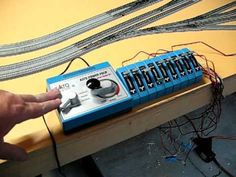 a hand is pointing at an electronic device on a table with wires attached to it