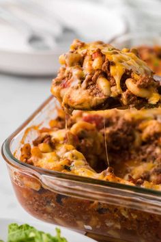 a casserole dish with meat and cheese being lifted from the casserole