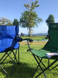 two lawn chairs sitting on top of a lush green field