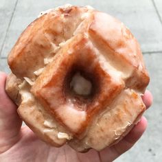 a hand holding a glazed donut with icing