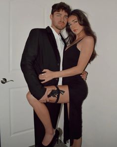 a man and woman posing for a photo in front of a door with their arms around each other