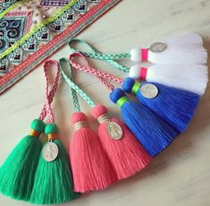 four tasselled keychains with different colors and designs on them sitting on a table