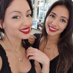 two beautiful young women standing next to each other with red lipstick on their lips and wearing necklaces