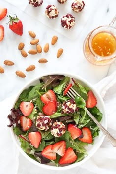 a salad with strawberries and almonds on the side