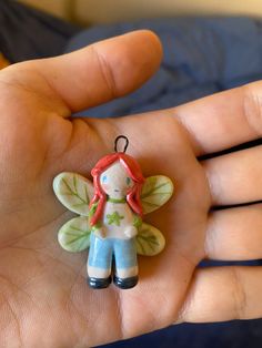 a hand holding a small ceramic fairy ornament in it's palm