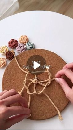 a person is making a craft with yarn and buttons on a round tablecloth that has been made from corks