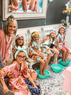 a group of women sitting on top of chairs in matching robes and headbands