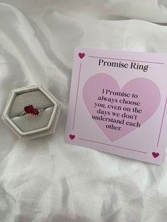 a pink ring box with a red rose on it next to a valentine's day card