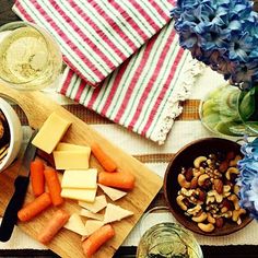 a table topped with bowls of food and plates filled with vegetables next to wine glasses