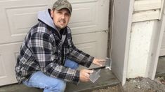 a man sitting on the ground in front of a garage door holding an open laptop computer