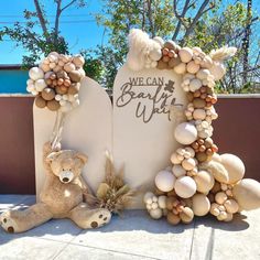 a teddy bear sitting in front of a stone sign with rocks and shells around it