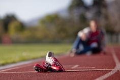 a pair of red shoes sitting on top of a running track