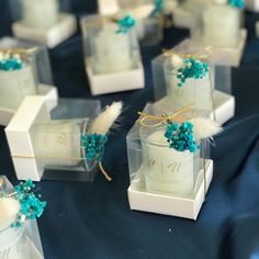 small white boxes with teal flowers and feathers on blue cloth covered tablecloths