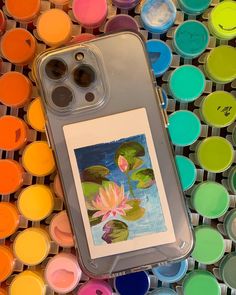 an iphone case sitting on top of some paint cans with water lilies in them