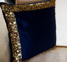 a blue pillow with gold sequins on it sitting on a couch next to a remote control