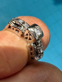 a close up of a person's hand holding a ring with two diamonds on it