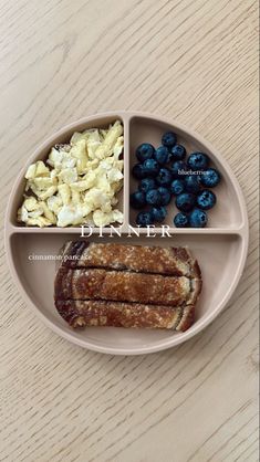 a plate with blueberries, crackers and other food on it that is divided into four sections