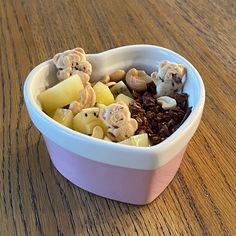 a bowl filled with fruit and nuts on top of a wooden table