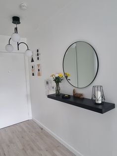 there is a black shelf with flowers on it and a mirror hanging above the wall