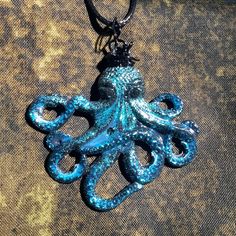 "Here we have a beautiful Octopus necklace. I hand-painted it black & added aqua blue & dark blue glitter for an ombre effect. It's sealed for protection which gives it a \"wet look.\" The top is wire-wrapped for better positioning on your neck. Lightweight, unique, & only one available. The actual pendant measures about 2 inches long. Comes with a black cord, but you can message me to see if I have a different cord color instead. Feel free to message me with any questions or for a custom order! :) Check out my other necklace listings! If you'd like more than one piece, message me & I'll give you a discount!  *UPDATE May 25th: price reduced!* Free U.S. Shipping! International is set for this item - read my shop announcement for more details. Follow @myfellowvillains on Instagram for update Octopus Necklace, Sea Life Jewelry, Wet Look, Ombre Effect, Blue Ombre, Blue Glitter, Octopus, Aqua Blue, Sea Creatures