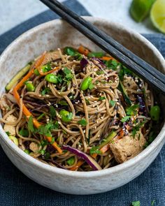 a bowl filled with noodles and vegetables next to chopsticks