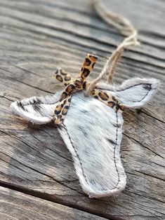 an animal print cow skin ornament hanging from a rope on wooden planks