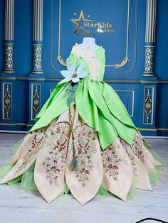 a dress made out of cloths and fabric with flowers on the top, sitting in front of a blue wall