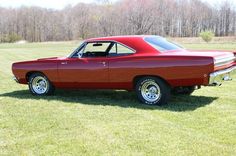 an old red car is parked in the grass