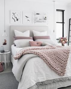 a bed with white sheets and pink blankets