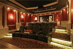 a large room with red walls and black leather chairs on the carpeted flooring