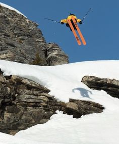 the skier is in mid air doing a trick on the snow covered mountain slope with his skis