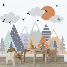 two chairs and a table in front of a wall mural with birds flying over the mountains