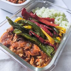 a meal in a plastic container with rice and vegetables on the table next to it