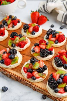 small fruit pizzas are arranged on a wooden board