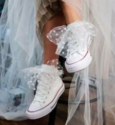 a woman in white sneakers is sitting on a chair with a veil over her legs