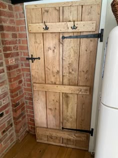 a white refrigerator freezer sitting next to a wooden door in a room with brick walls