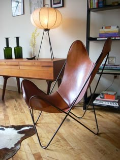 a brown leather chair sitting in front of a wooden table with a lamp on top of it