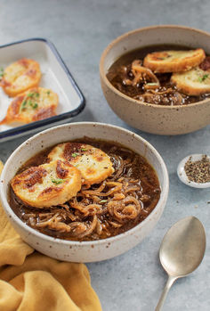 two bowls filled with soup and bread on top of a table