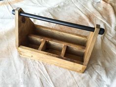 an empty wooden box with two compartments and a black handle on top of a white sheet