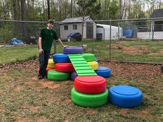 a man standing next to a pile of colorful tires