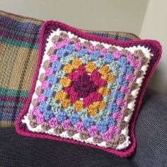 a crocheted square pillow sitting on top of a couch